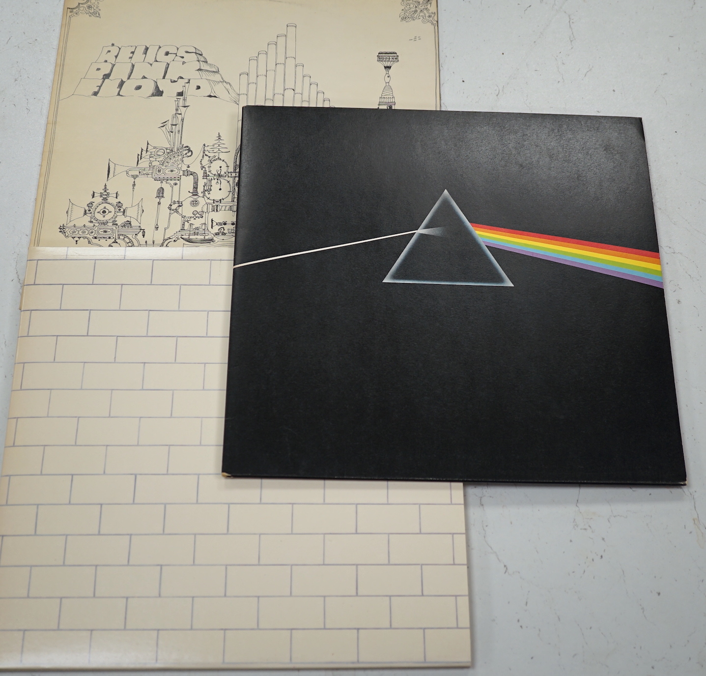 Three Pink Floyd LP record albums; Dark Side of the Moon, on Harvest SHVL 804, with both posters and black inner sleeve, The Wall, on Harvest SHSP 4111 A 2U, Relics, on Starline, SRS 5071